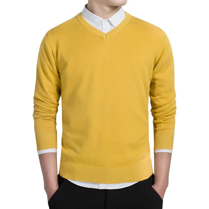 Man wearing mustard yellow V-neck sweater over white collared shirt with black pants