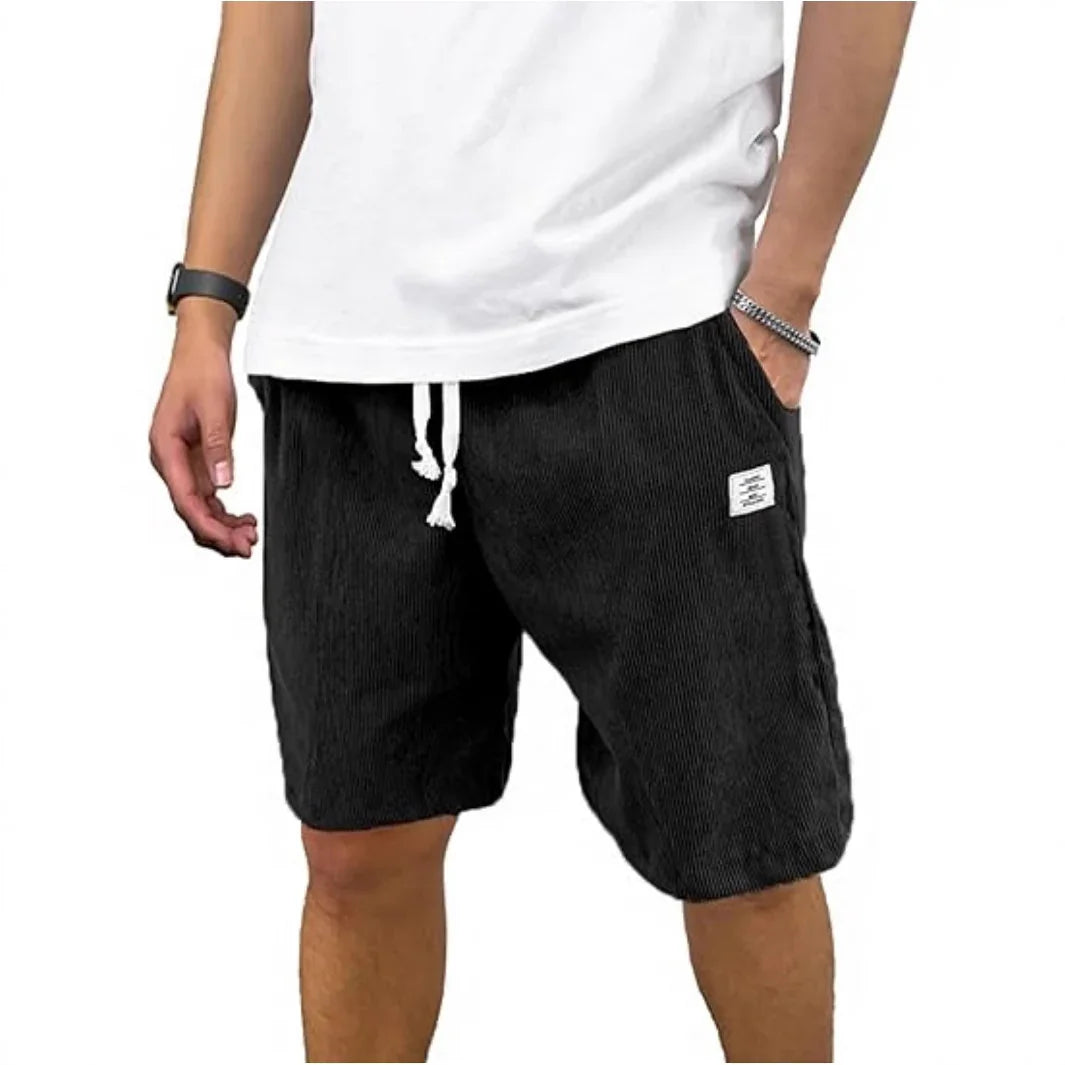 Man wearing black corduroy drawstring shorts with pockets and a white tank top