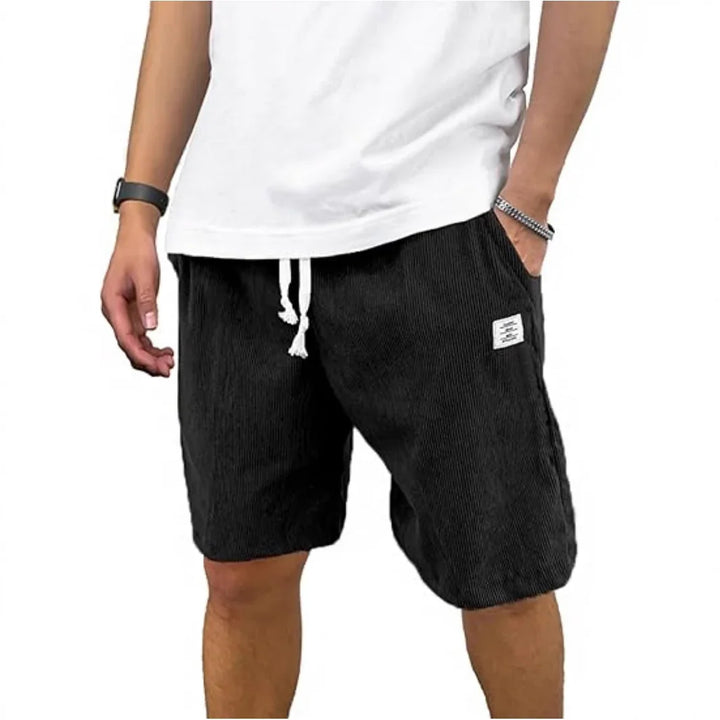 Man wearing black corduroy drawstring shorts with pockets and a white tank top