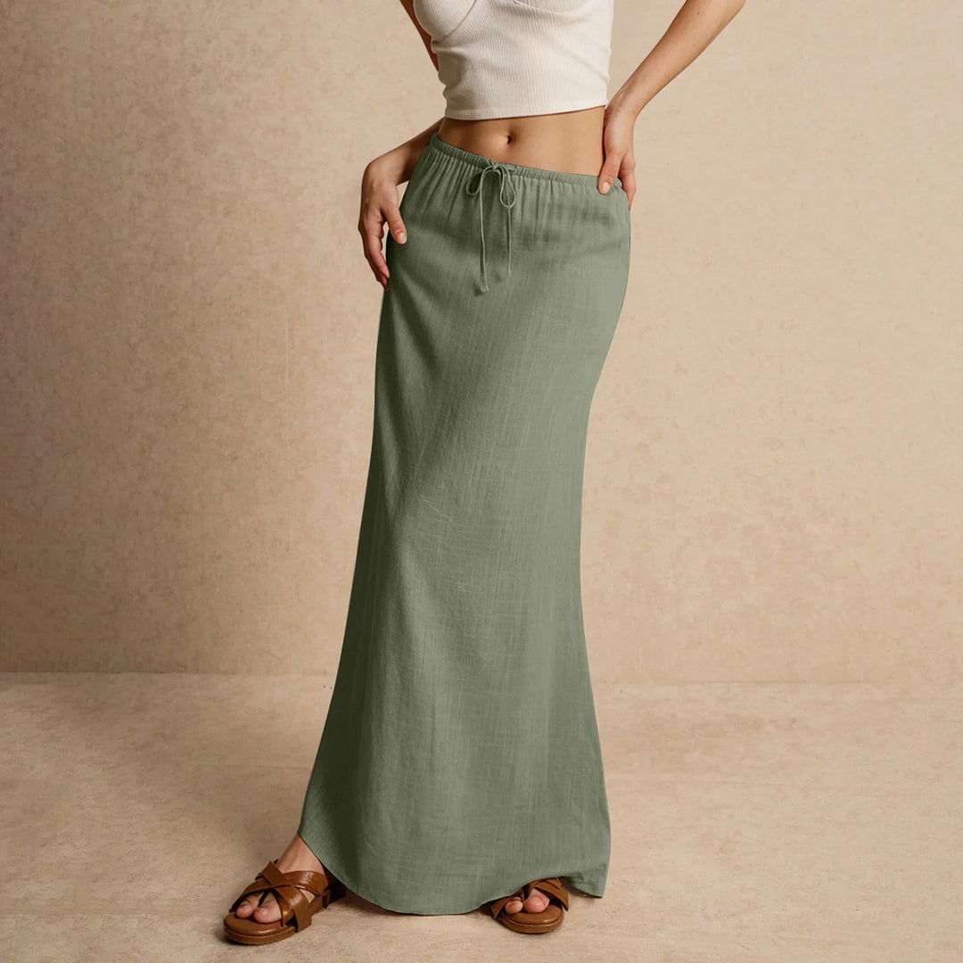 Woman wearing olive green maxi skirt with drawstring waist and brown sandals on beige background