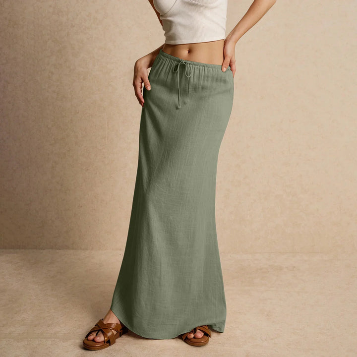 Woman wearing olive green maxi skirt with drawstring waist and brown sandals on beige background