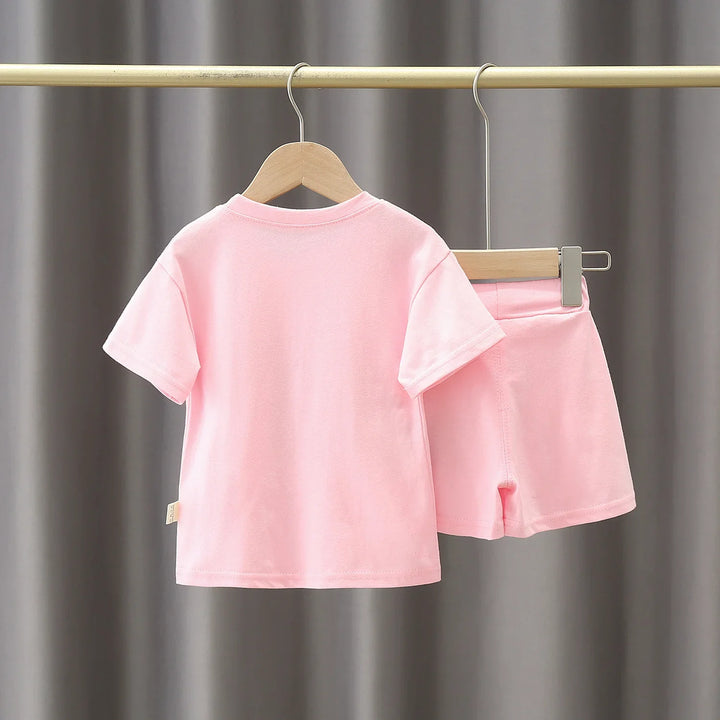 Soft pink short sleeve t-shirt and matching shorts set for kids hanging on wooden hangers