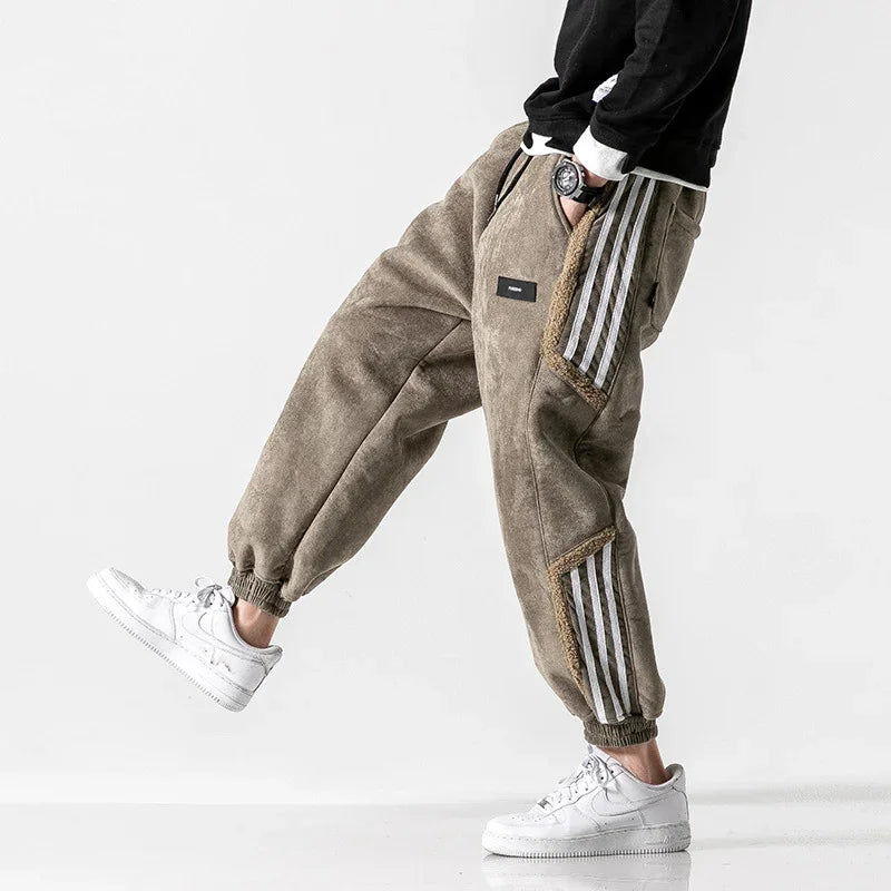Person wearing brown fleece jogger pants with side stripes and white sneakers, styled in casual fashion