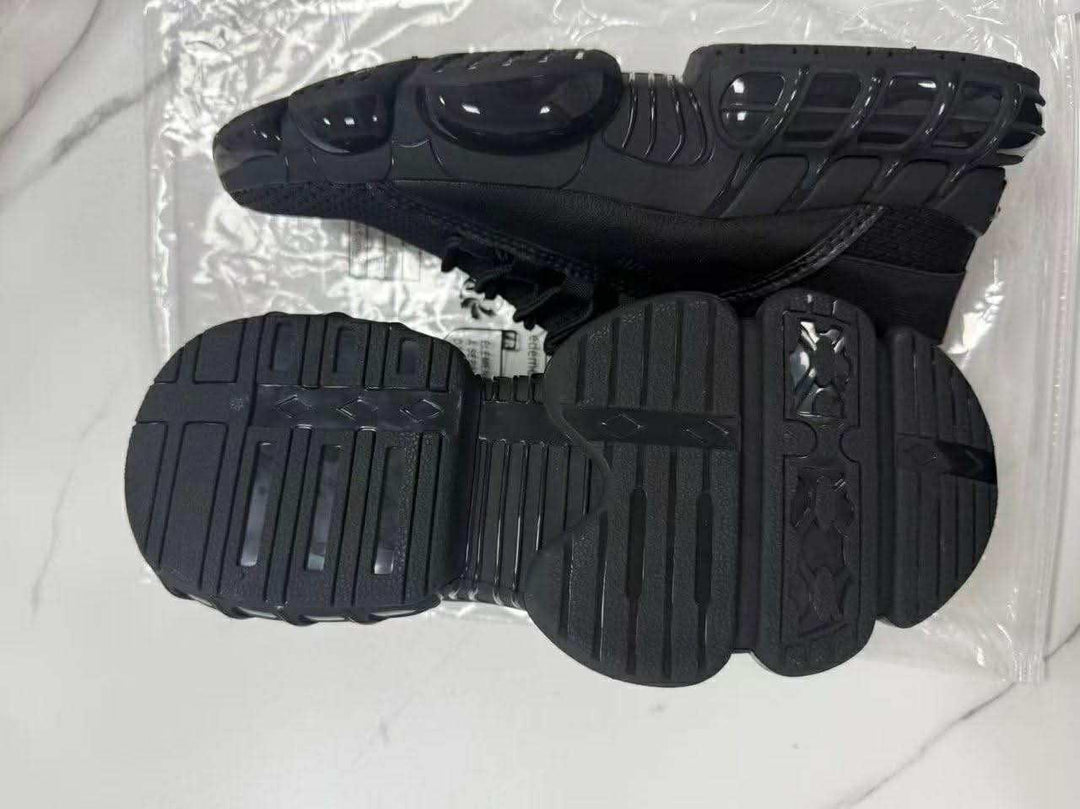pair of black athletic shoes with unique segmented soles on white marble surface