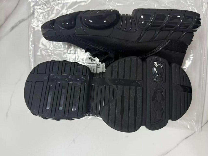 pair of black athletic shoes with unique segmented soles on white marble surface