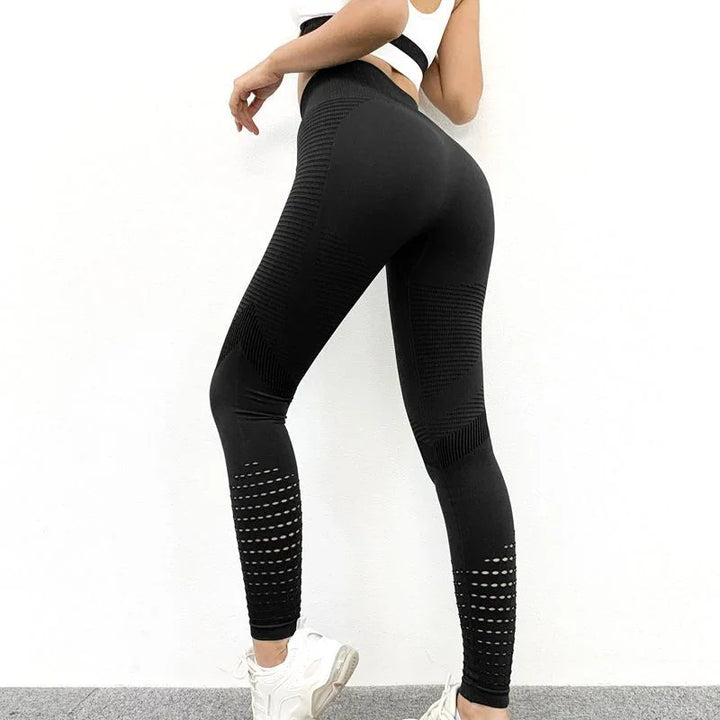 Woman wearing black textured high-waist workout leggings and white sneakers against white wall