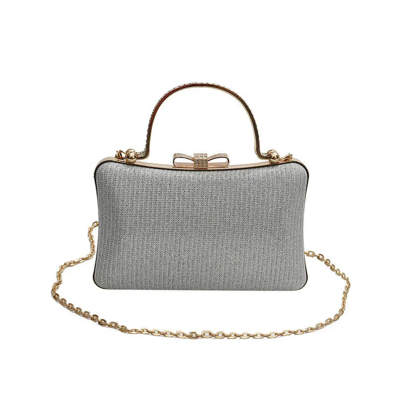 Silver glitter evening clutch handbag with gold chain strap and bow clasp