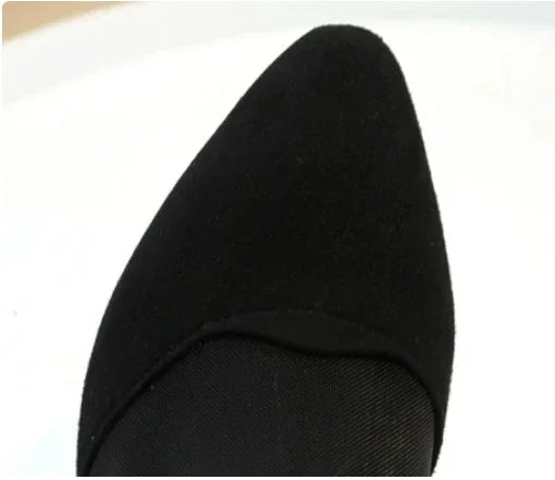Close-up of a black pointed toe suede shoe on a white background
