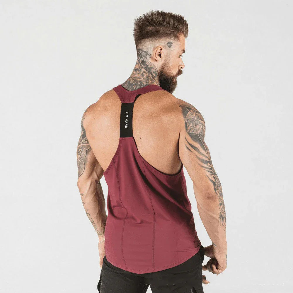 Muscular tattooed man wearing maroon racerback tank top with black strap reading Go Hard