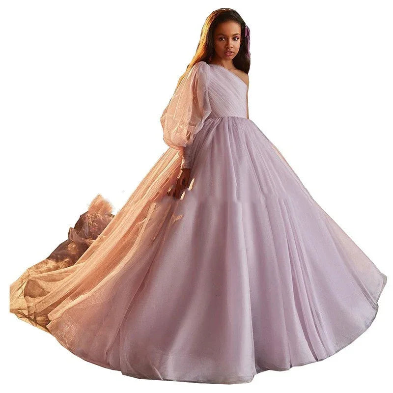 Young girl wearing a lavender one-shoulder ball gown with puffed sleeve and long tulle train