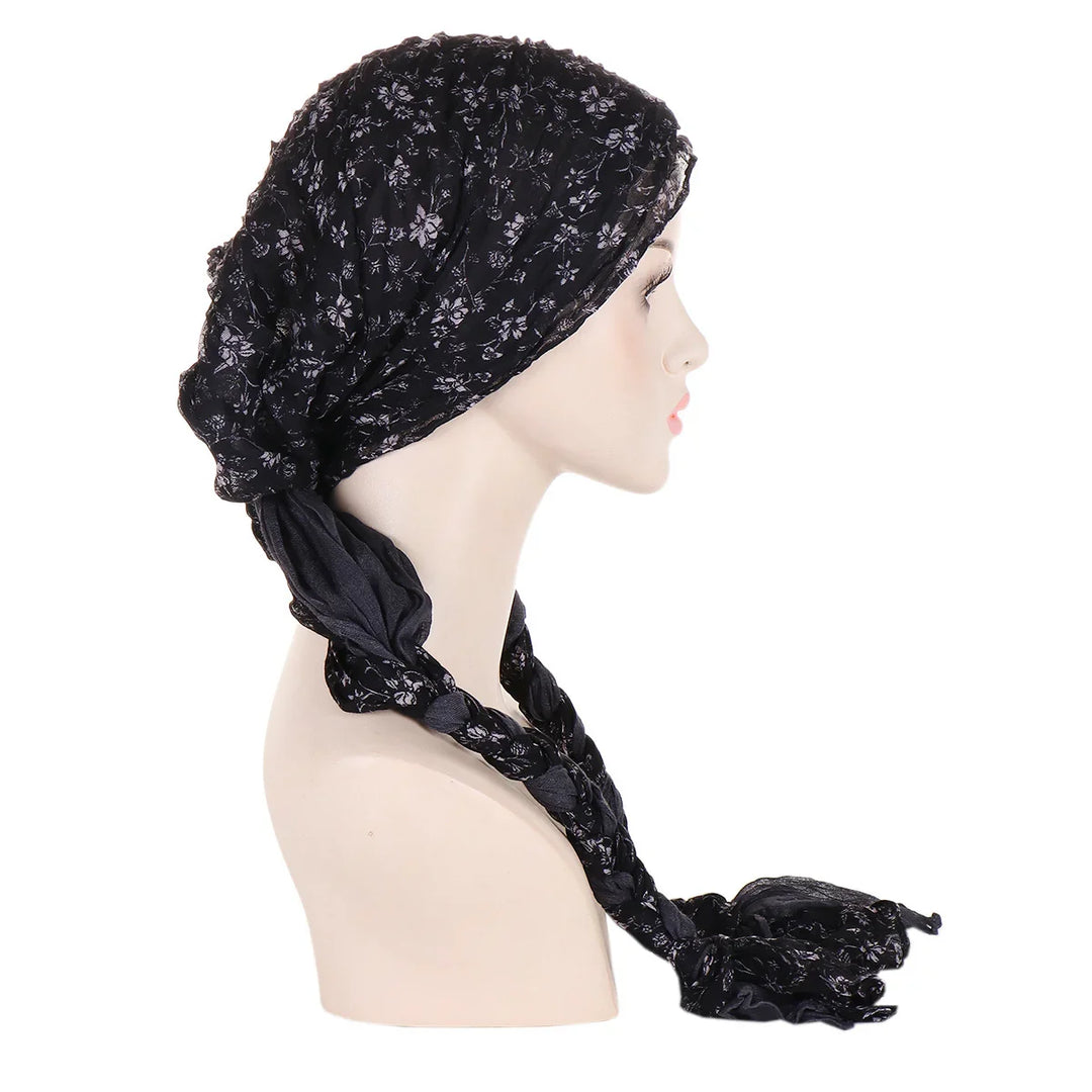 Side view of mannequin wearing black floral patterned headscarf with braided ends