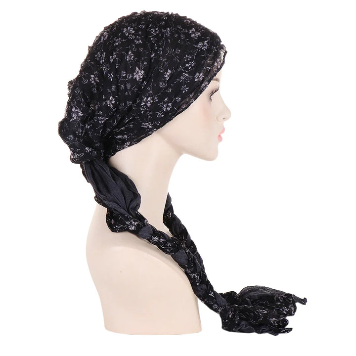 Side view of mannequin wearing black floral patterned headscarf with braided ends