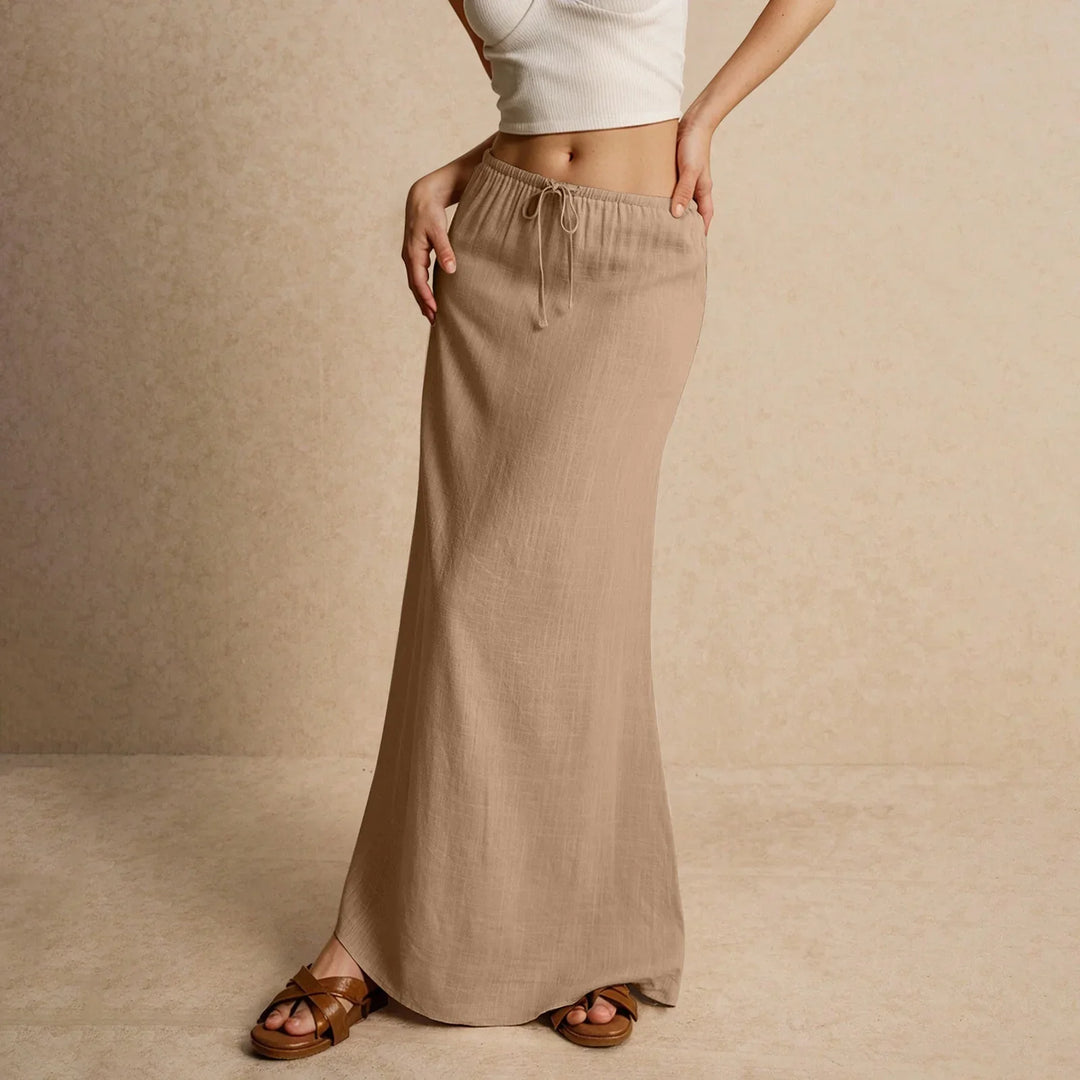Woman wearing beige maxi skirt with drawstring waist and white crop top, standing on neutral background