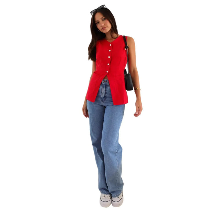 Woman wearing red sleeveless buttoned top, blue jeans, white sneakers, black shoulder bag