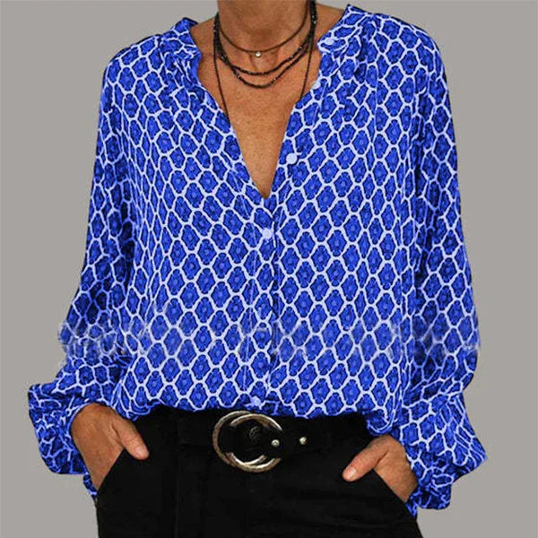 Woman wearing blue patterned button-up blouse with black pants and layered necklaces