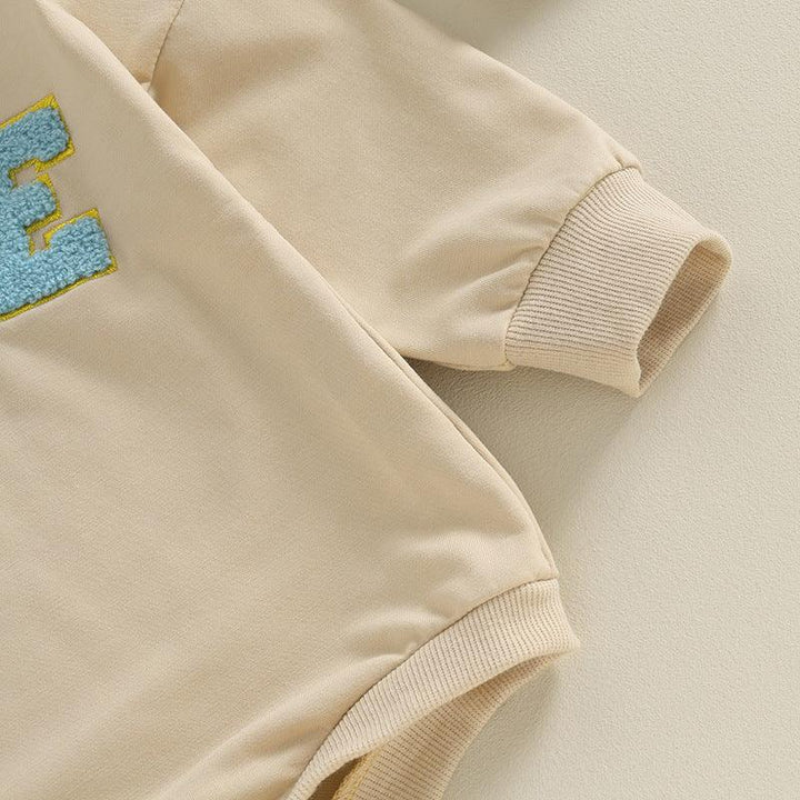 Beige sweatshirt sleeve and hem with ribbed cuffs and blue textured letter embroidery