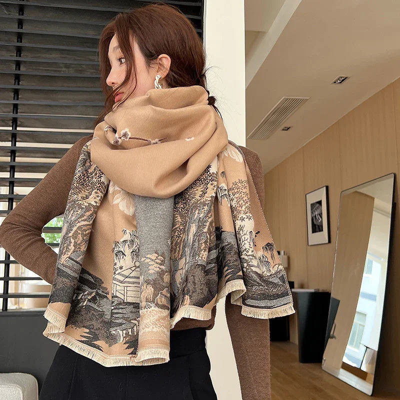 Woman wearing large beige and brown scarf with landscape print, brown long-sleeve top, indoor setting