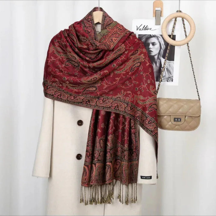 Red paisley patterned pashmina scarf draped over white wool coat with beige quilted handbag