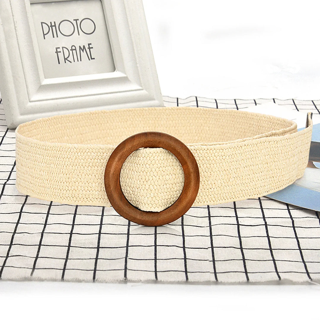 Beige woven belt with round wooden buckle placed on black and white grid fabric