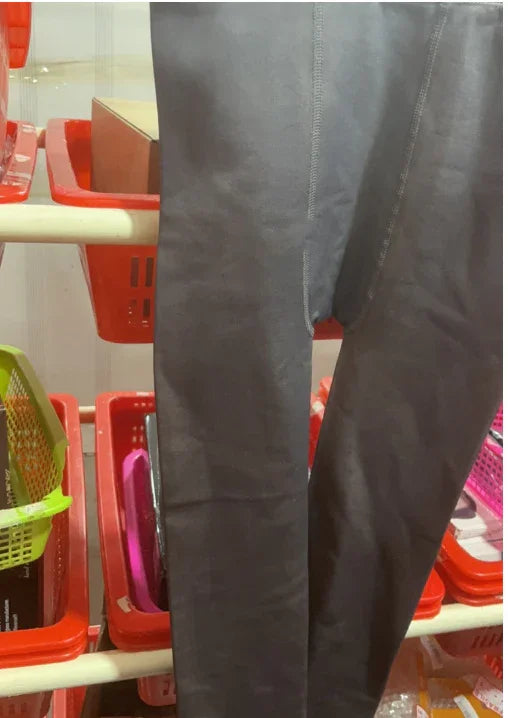 Close-up of black leggings displayed over red and green plastic shopping baskets in a retail setting
