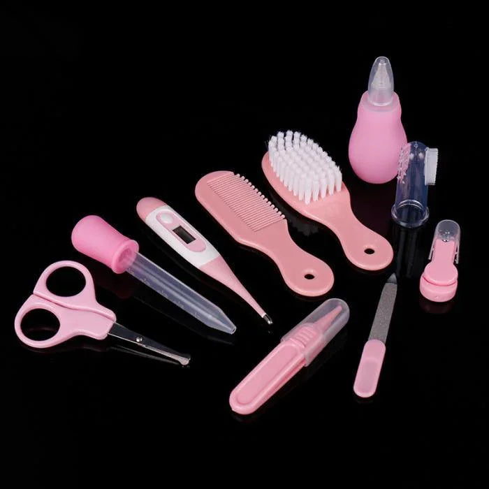 Pink baby grooming kit with scissors, thermometer, combs, brush, nail file, nasal aspirator on black background
