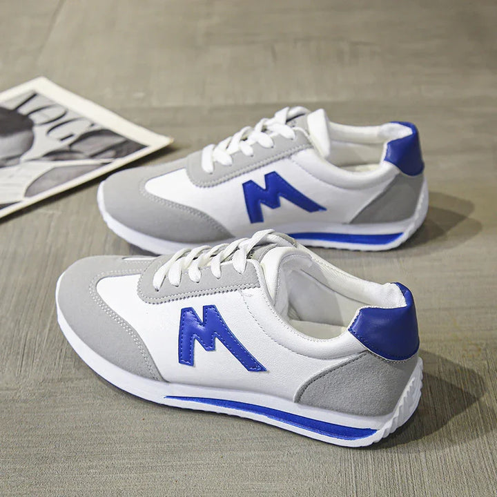 Pair of white and gray casual sneakers with blue accents and laces on wooden floor