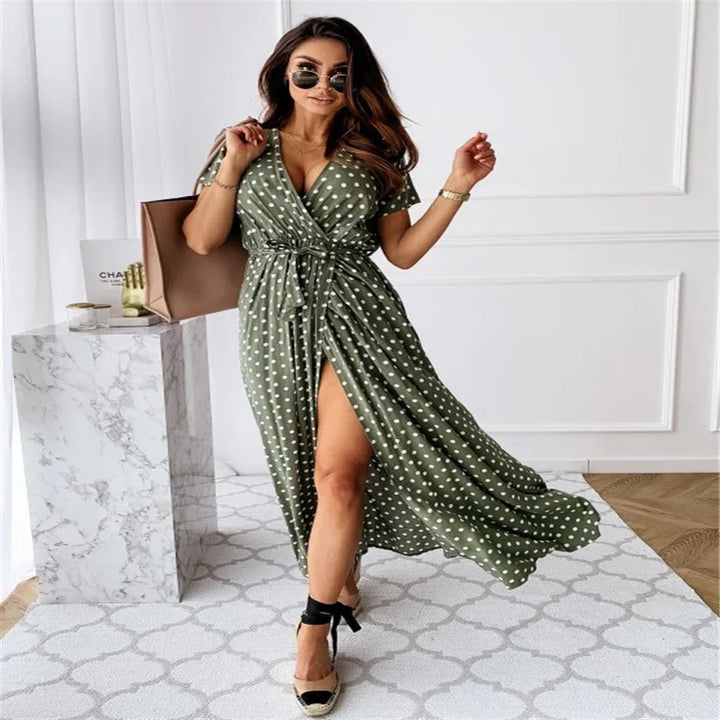 Woman wearing olive green polka dot wrap dress with slit, black sunglasses, beige espadrilles, and brown tote bag