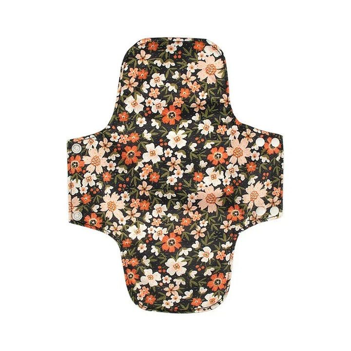 Reusable fabric menstrual pad with floral pattern in orange, white, and green on black background