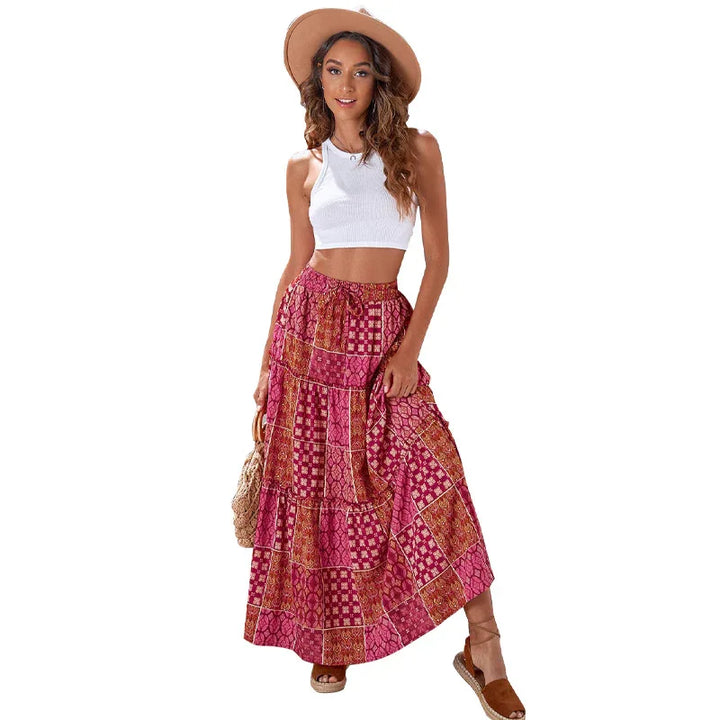 Woman wearing a white crop top, wide-brim hat, and patterned red patchwork maxi skirt with sandals