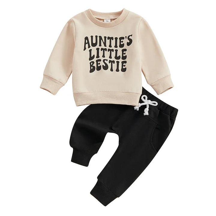 Beige toddler sweatshirt with 'Auntie's Little Bestie' text and black jogger pants with white drawstring