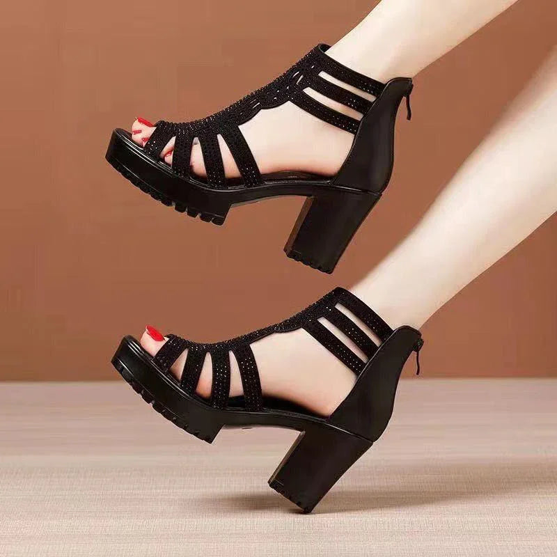 Black high-heel platform sandals with ankle straps worn on feet with red nail polish against a brown background