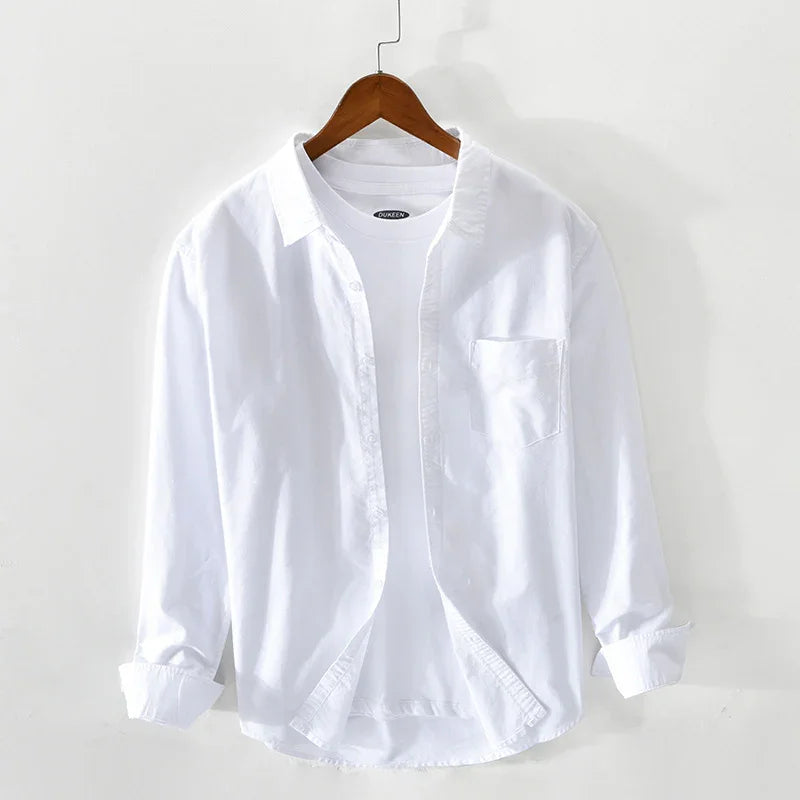 White casual shirt with button-down front and chest pocket on wooden hanger against white background