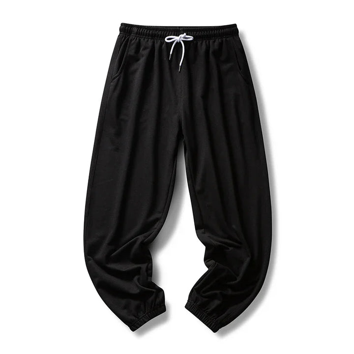 Black casual jogger pants with elastic cuffs and white drawstring on white background