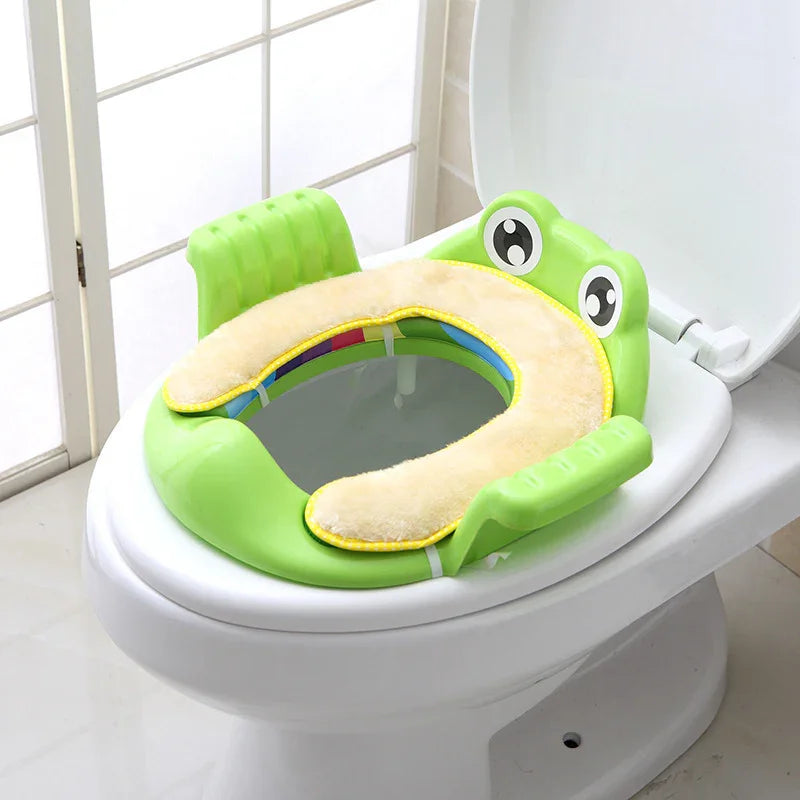 Green frog-themed padded toddler potty training seat with armrests on white toilet