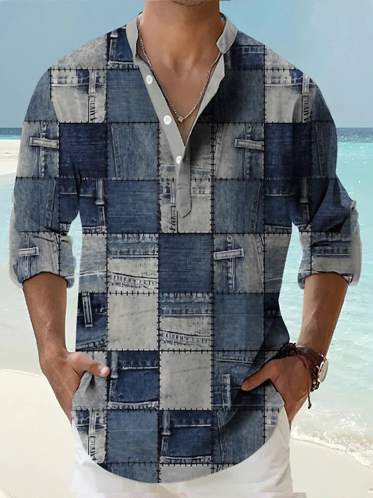 Man wearing blue patchwork denim shirt with rolled sleeves at the beach, hands in pockets