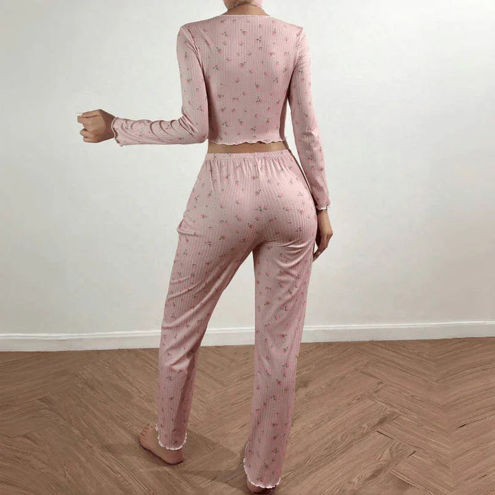 Back view of woman wearing pink floral ribbed pajama set with long sleeves and pants on wooden floor