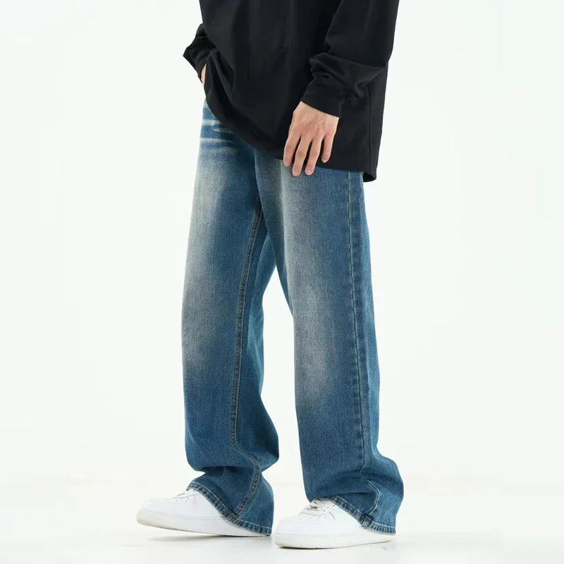 Person wearing faded wide-leg blue jeans and white sneakers with a black long-sleeve top