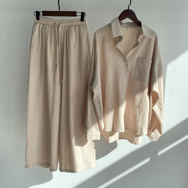 Beige linen long sleeve button-up shirt and matching elastic waist pants hanging on wooden hangers