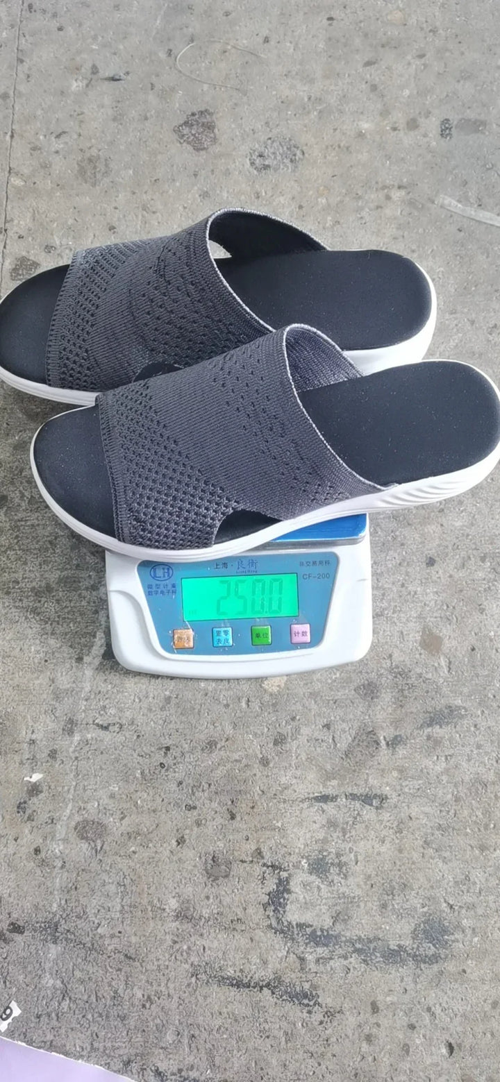 Black open-toe knit slippers on digital scale showing 250 grams on concrete floor