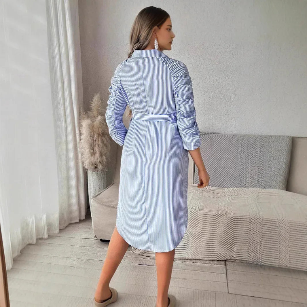 Woman wearing a blue and white striped belted shirt dress with ruched sleeves indoors