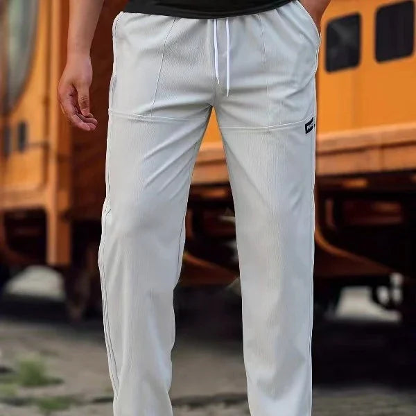 Close-up of man wearing white casual pants with side pockets and drawstring waist near yellow train