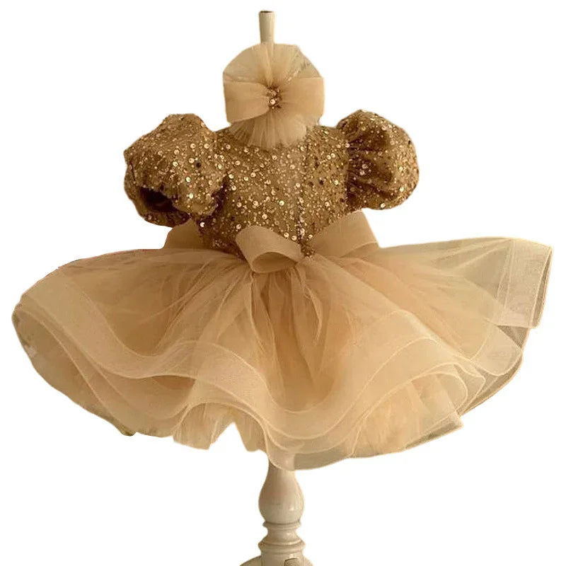 Elegant gold sequin baby dress with puff sleeves and tulle skirt on white mannequin