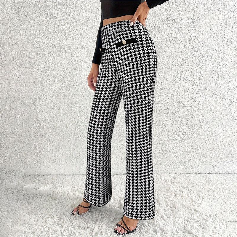 Woman wearing high-waisted black and white houndstooth pants with button detail, paired with black crop top and strappy heels