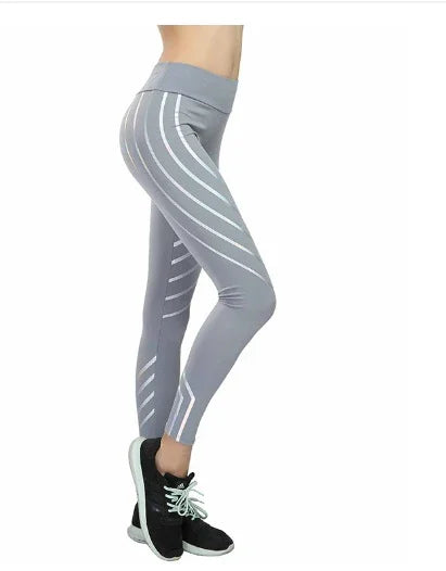 woman wearing gray high-waisted leggings with white stripes and black sneakers on white background