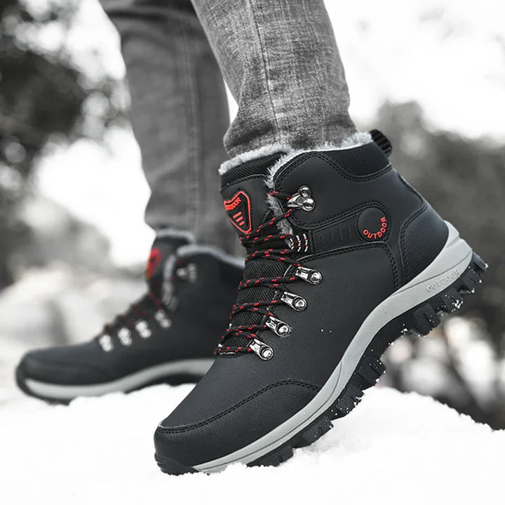 Black outdoor hiking boots with red accents and fur lining worn on snow