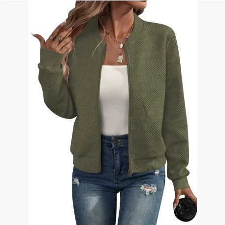 Woman wearing olive green textured zip-up jacket with ribbed cuffs, paired with white top and ripped jeans