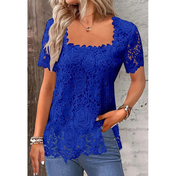 Woman wearing royal blue lace top with short sleeves and scalloped hem, paired with light blue jeans
