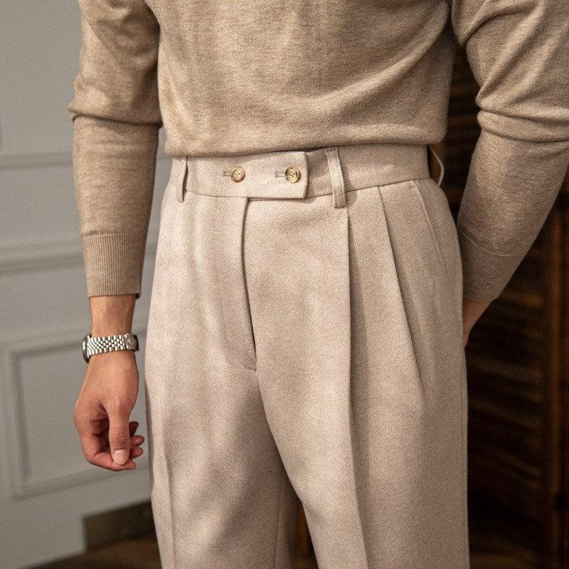 Close-up of man wearing beige pleated trousers with side adjuster buttons and beige sweater
