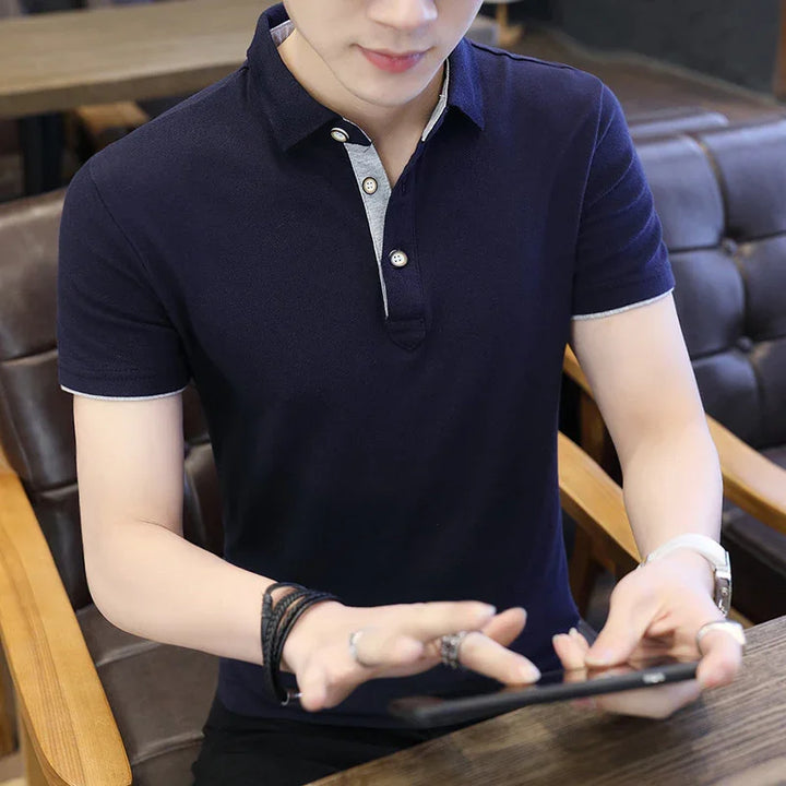 Man wearing navy blue polo shirt sitting in a cafe using a smartphone