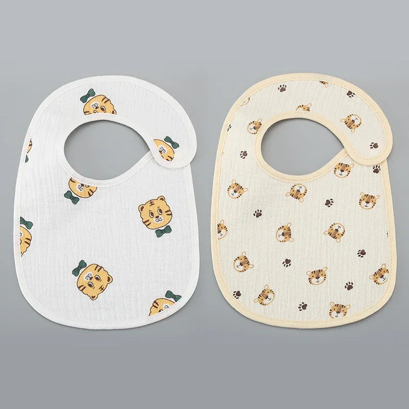 Two baby bibs with tiger face and paw print patterns on white and cream backgrounds